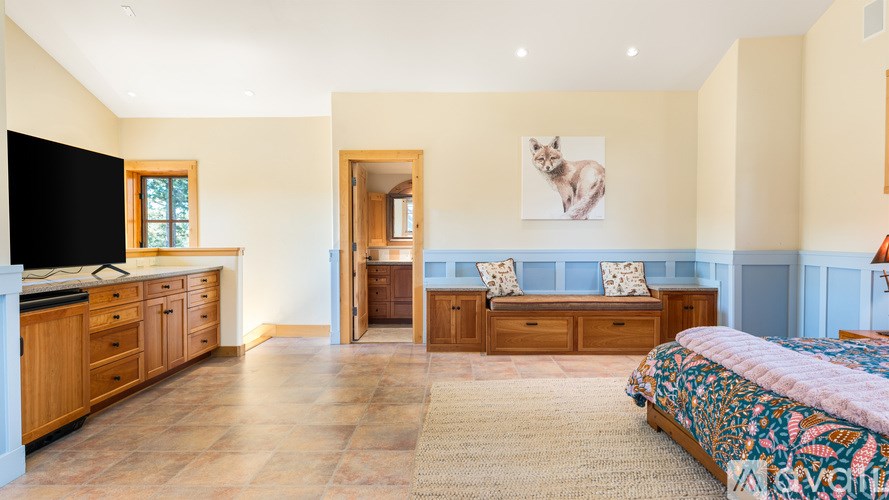 A bedroom with a bed, dresser, and a television.