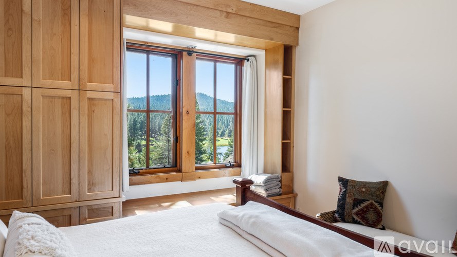 A bedroom with a large bed and a view of the mountains through the window.