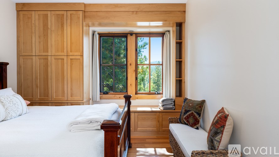 A bedroom with a bed, a couch, and a window with wooden panels.
