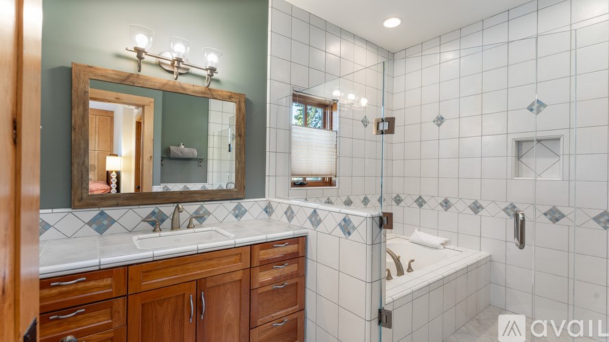 A bathroom with a mirror, sink, and tiled walls.