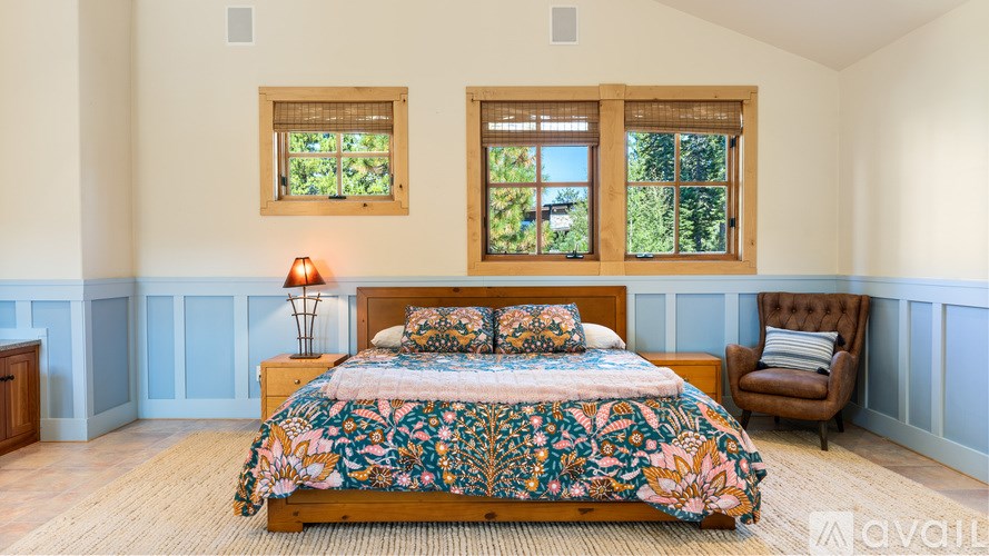 A bedroom with a large bed and a chair.