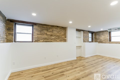 A room with wooden floors and a brick wall.
