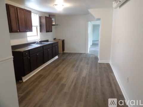 A kitchen with dark wood cabinets and a light wood floor.