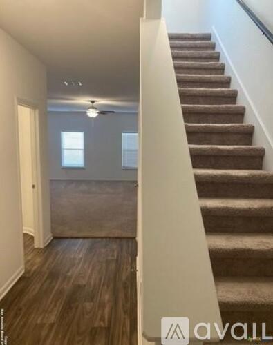 A staircase with a carpeted runner and wooden steps leads up to a second floor.