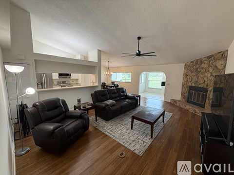 A living room with a black leather couch and a wooden floor.