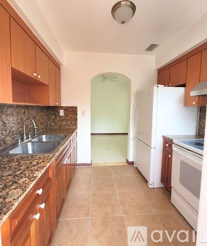 A kitchen with a white refrigerator and brown cabinets.