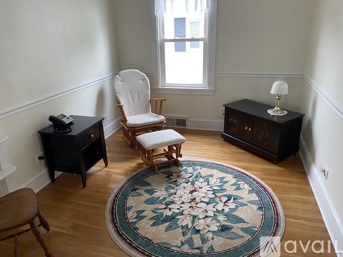 A room with a chair, a table, and a rug.