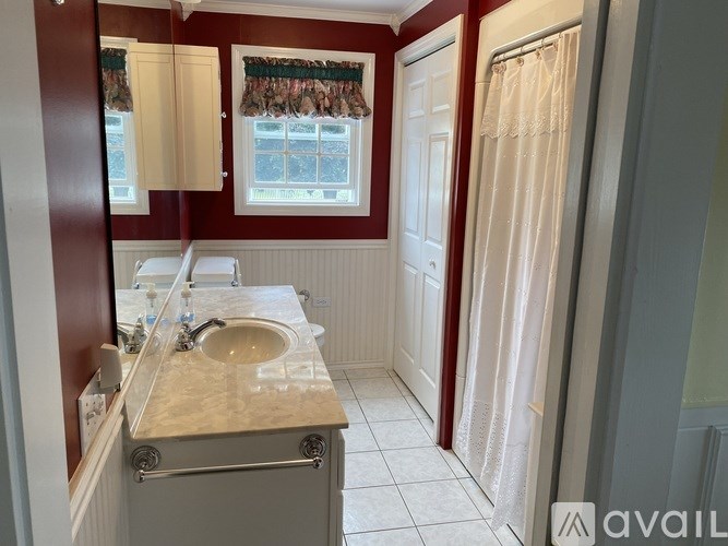 A bathroom with a double sink vanity and a window with curtains.
