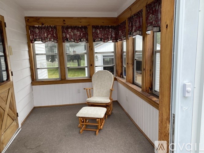 A chair and ottoman are placed in a sunny room with a window.