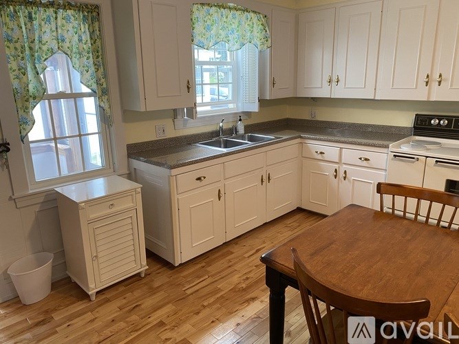 A kitchen with wooden floors and white cabinets.