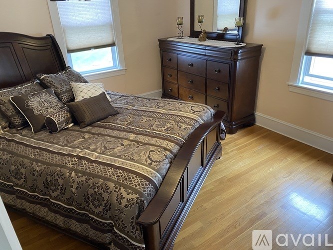 A bedroom with a bed, dresser, and window.