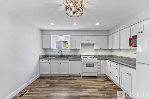 A kitchen with white cabinets and a wooden floor.