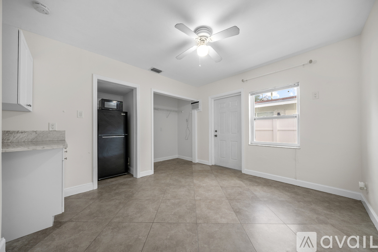 A spacious room with a ceiling fan and a refrigerator.