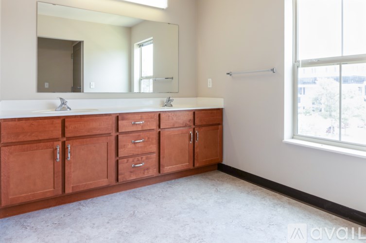 A bathroom with a white counter top and brown cabinets.