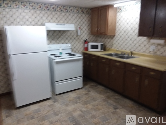 A kitchen with a white fridge, white stove, and brown cabinets.
