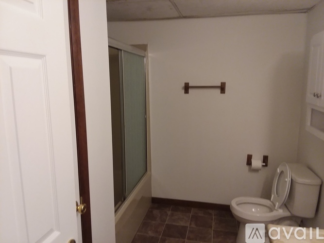 A bathroom with a toilet, a towel bar, and a shower.