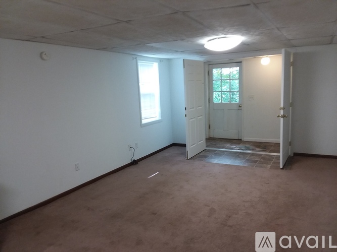A room with a carpeted floor and a door leading to another room.