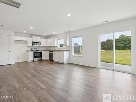A spacious kitchen with white cabinets and a wooden floor.