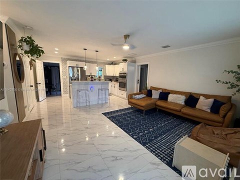 A living room with a brown couch and a white kitchen in the background.