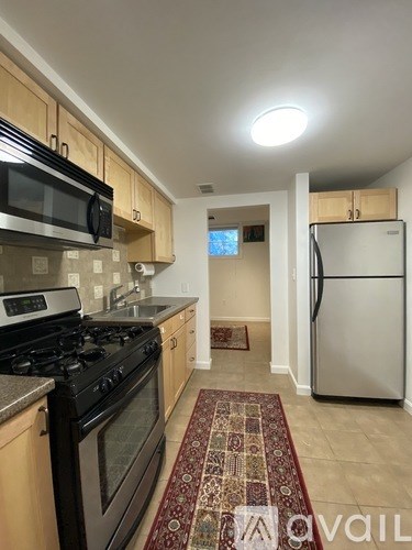 A kitchen with a black stove top oven and a black microwave above it.