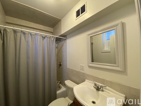 A bathroom with a toilet, sink, and shower curtain.