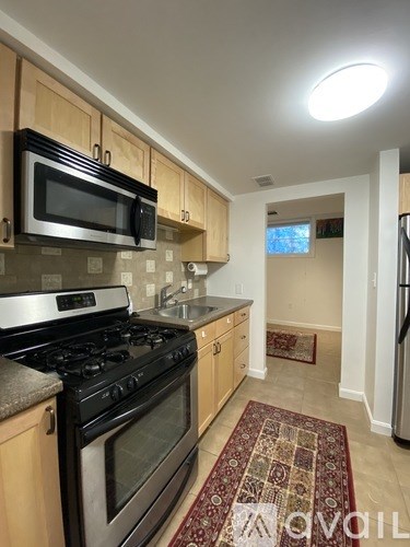 A kitchen with a black microwave above a stove and wooden cabinets.