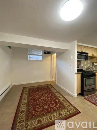 A kitchen area with a rug on the floor and a microwave on the counter.