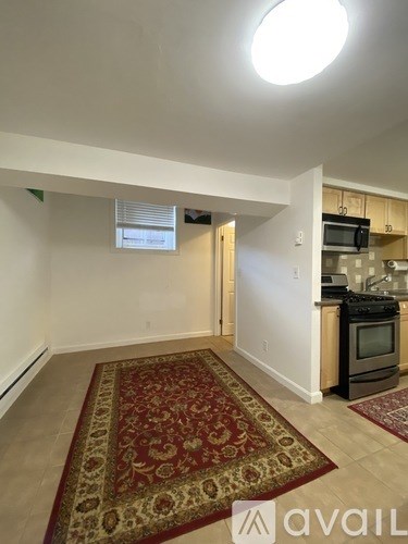 A kitchen area with a rug on the floor and a microwave on the counter.