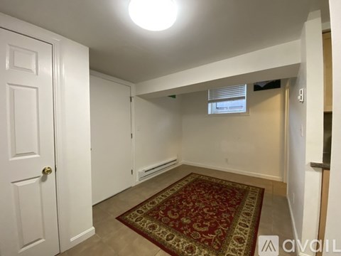 A room with a rug on the floor and a door on the left.