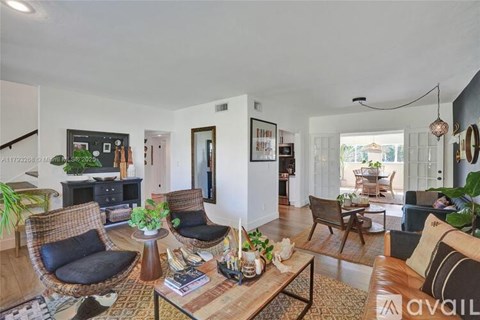 A living room with a brown wicker chair and a black cushion.