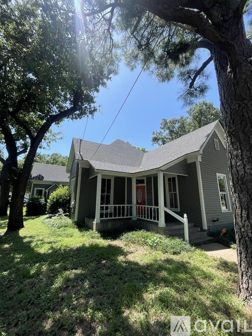 A house with a porch and a tree in front of it.