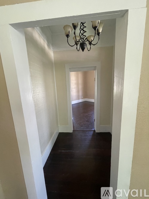 A hallway with a chandelier and white walls.