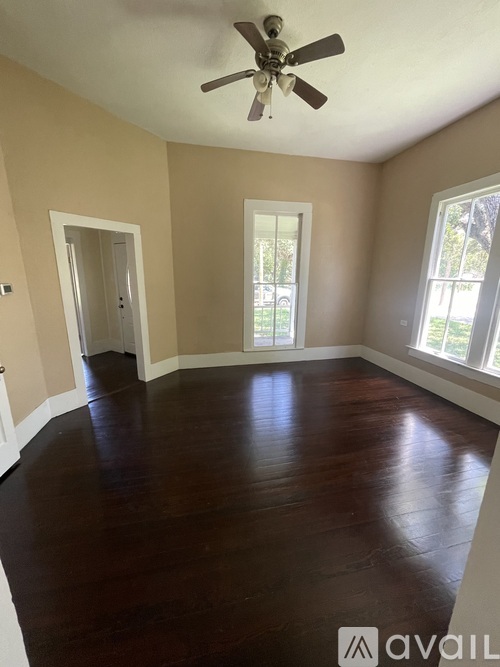 A room with a ceiling fan and hardwood floors.