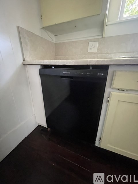 A black dishwasher is in a kitchen with white walls.