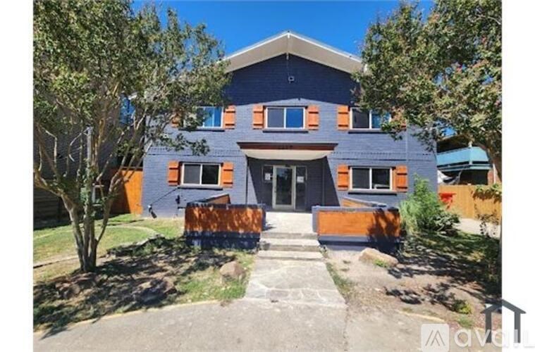 A modern house with a flat roof and orange shutters.