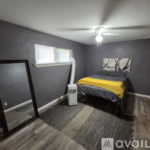 A bedroom with a bed, a window, and a fan.