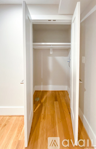 A hallway with a wooden floor and white walls.