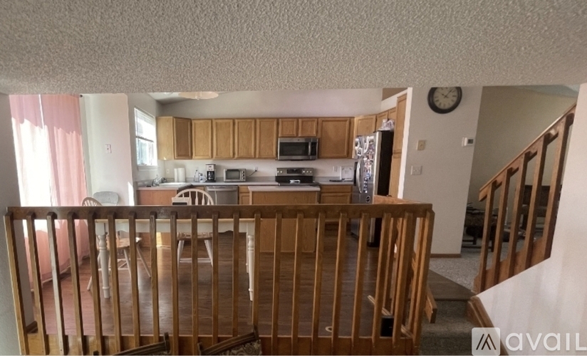 A kitchen with wooden cabinets and a clock on the wall.