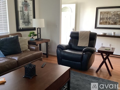 A living room with a black leather chair and a brown couch.