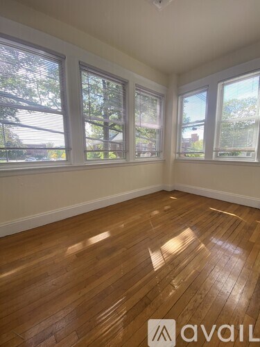 A room with wooden floors and three windows.