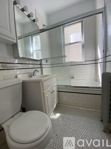 A white toilet sits in a bathroom with a tiled floor and a glass shower door.
