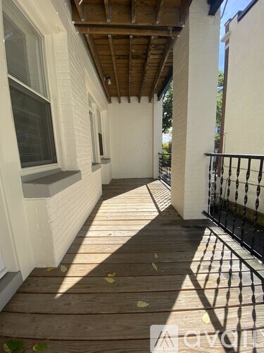 A wooden deck with a metal railing and a white house.