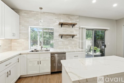 A modern kitchen with white cabinets and a marble countertop.