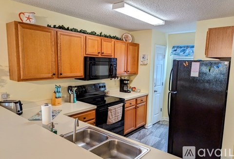 A kitchen with wooden cabinets and a black fridge.