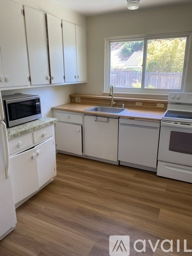 A kitchen with white appliances and wooden floors.