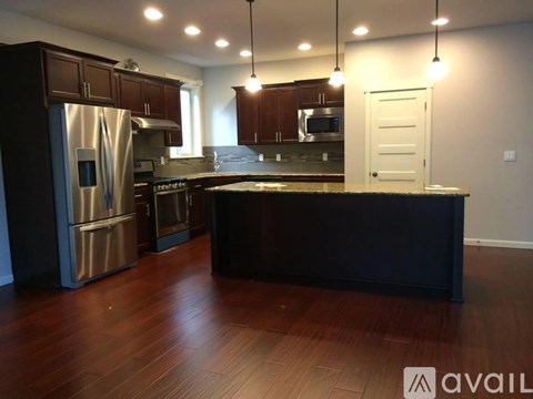 A kitchen with dark wood floors and stainless steel appliances.