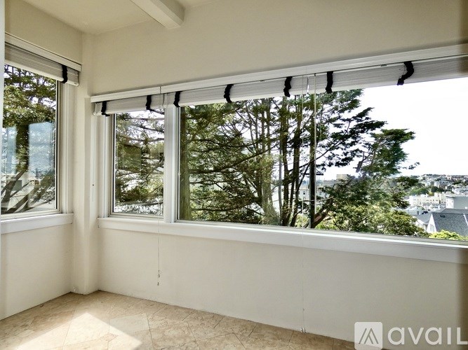 A room with a large window overlooking a tree-filled landscape.