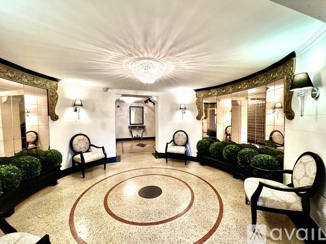 A well-lit, elegant room with a circular design on the floor and a chandelier hanging from the ceiling.