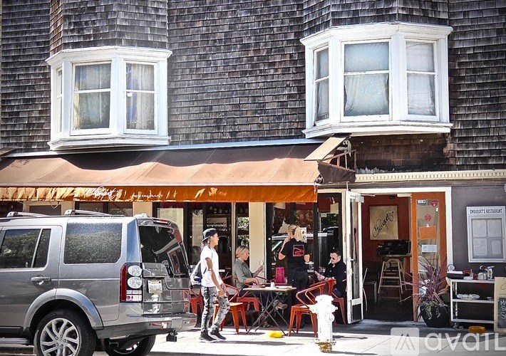 A silver SUV is parked in front of a building with a brown awning.