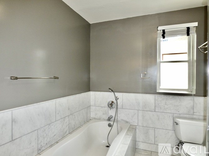 A bathroom with a white tub and a window.